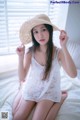 A woman sitting on a bed wearing a straw hat.