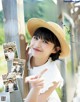 A woman in a straw hat pointing at the camera.