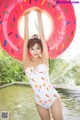 A woman in a bathing suit holding an inflatable donut.