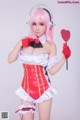 A woman in a maid outfit holding a heart shaped wand.