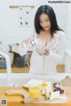 A woman pouring milk into a bowl on top of a wooden cutting board.