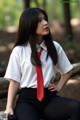 A woman in a white shirt and red tie sitting on a bench.